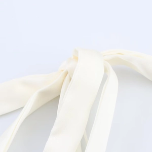 Gros plan d'un nœud en satin crème montrant la texture sergé et le brillant du tissu