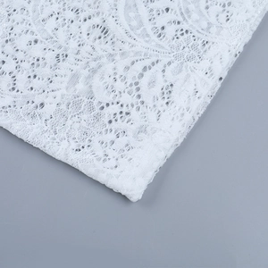 Dettaglio macro del tessuto in pizzo floreale bianco con ricami trasparenti