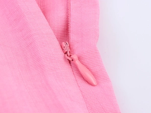 Macro view of pink dress showing high-quality invisible zipper and woven fabric texture