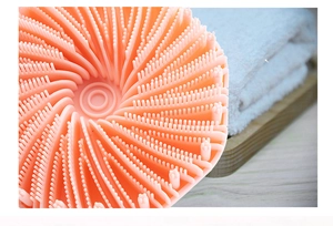 Close-up of pink silicone bath brush bristles showing soft texture on white towel