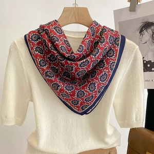 Vintage red and blue paisley silk scarf displayed on a wooden hanger with knitwear