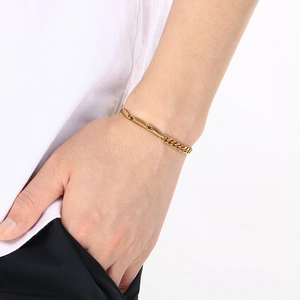 Close-up of golden Cuban and bamboo link mixed chain bracelet worn by a model