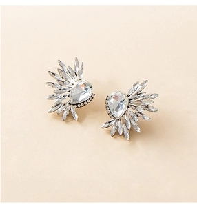 Macro detail of winged rhinestone earrings with pear-cut central stone in gold setting