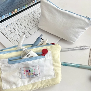 Close-up of canvas pencil pouches with multi-layer storage and colorful embroidery details