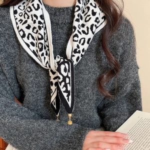 Detail of leopard print knitted scarf with golden ball pendant and refined edge stitching