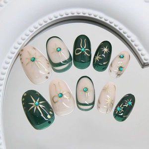 Short oval fake nails in glittery vintage green with starburst patterns and blue gems