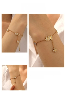 Detailed close-up of a gold-plated bracelet featuring enamel butterfly and clover charms