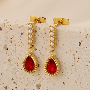Macro de boucles d'oreilles vintage dorées avec cristaux rouges et perles sur pierre