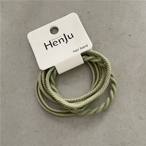 Close-up of green elastic hair band set with twisted and smooth textures on card