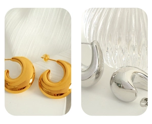 Polished gold and silver crescent hoop earrings shown on textured background