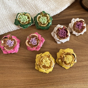 Détail de boucles d'oreilles fleurs vintage colorées avec bords dorés en rose blanc vert et jaune