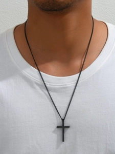 Detail einer mattschwarzen Kreuzkette an einem männlichen Modell im weißen Shirt
