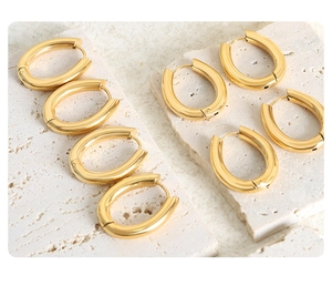 Close-up of gold geometric U-shape hoop earrings on a textured stone surface