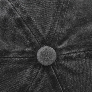 Detail view of the crown stitch and top button on a dark grey washed cotton baseball cap