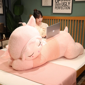 Close-up of a large pink plush sheep wearing a peach sweater on a cozy wooden bed
