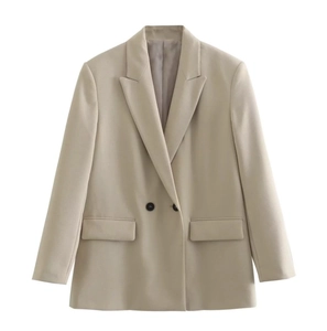 Detail of double-breasted beige blazer featuring peak lapels and symmetrical flap pockets
