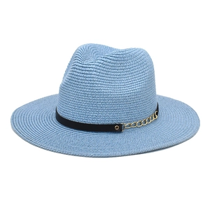 Detail of light blue straw fedora featuring a black ribbon and gold chain embellishment