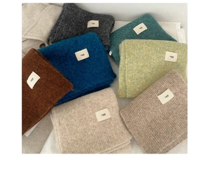 Stack of colorful wool blend knitted scarves in grey, blue, green, and beige tones