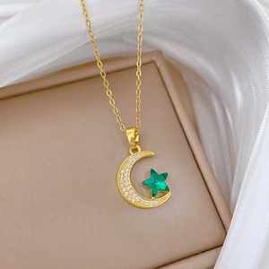 Golden crescent moon necklace with white crystals and a green star gemstone on a chain