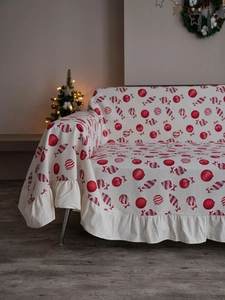 Close-up of beige Christmas sofa cover with red candy cane prints and ruffled edges