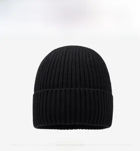 Detailed front view of black ribbed knit beanie featuring a metallic mountain logo badge
