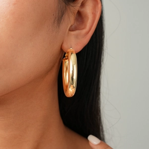 Polished gold-plated hoop earrings with smooth metallic finish shown on model