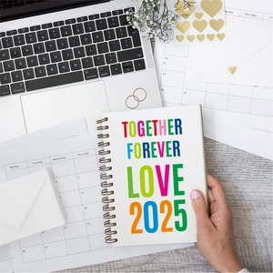 Detail of 2025 spiral notebook with colorful letters on a desk with stationery