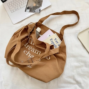 Flat lay of brown canvas tote bag with laptop and books for a casual lifestyle look