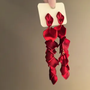 Detailed view of long matte red rose petal tassel earrings with a velvet-like texture