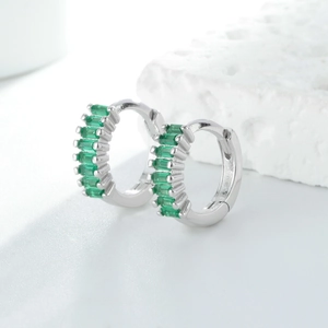 Détail de boucles d'oreilles créoles en argent S925 serties de zircons verts et fermoir charnière