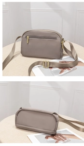 Macro detail of gray nylon crossbody bag showing smooth texture and golden zippers