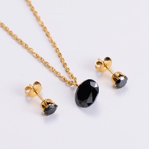 Detail of elegant gold jewelry set featuring faceted black oval and round gemstones