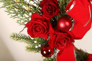 Close-up of Christmas wreath featuring red roses, pine needles and silver-edged ribbons