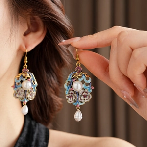 Detail of vintage enamel earrings with blue floral patterns and dangling teardrop pearls
