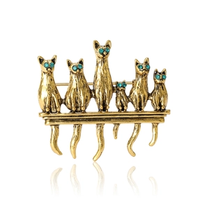Golden cat brooch featuring six cats with blue rhinestone eyes on a horizontal bar
