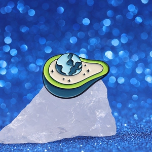 Creative enamel avocado earth brooch pin on crystal with blue bokeh background