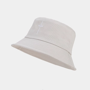 Detail of the embroidered white PEACE logo on a minimalist beige cotton bucket hat