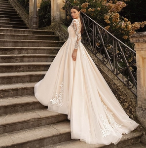 Detail of elegant long-sleeve champagne wedding dress with white lace appliques and train