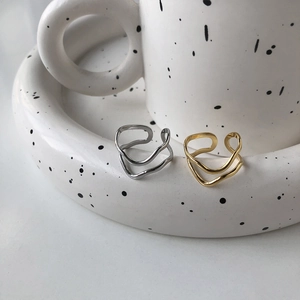 Minimalist wide wave irregular open rings in gold and silver finish on ceramic tray