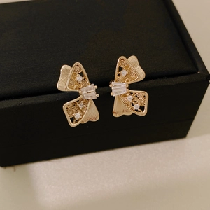 Gros plan de boucles d'oreilles nœud dorées avec zircons sur une boîte à bijoux