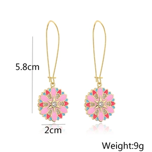 Dettagli di orecchini boho in oro con fiori in smalto rosa e blu e zirconi brillanti