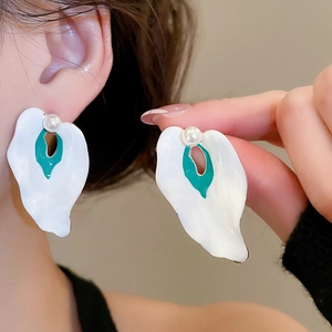 Close-up of calla lily earrings with white petals, green center, and pearl detail