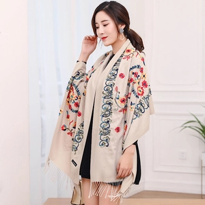 Detail view of ethnic floral embroidery and tassels on a beige cashmere pashmina shawl