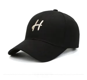 Detail of a black cotton baseball cap with white H letter embroidery and breathable holes