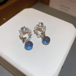 Vue macro de boucles d'oreilles en pierre bleue avec mini perles et détails floraux