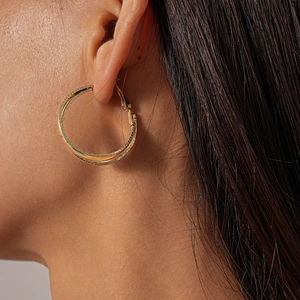 Close-up of elegant gold hollow layered cross hoop earrings worn by a model