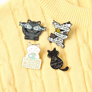 Cute enamel cat pins featuring coffee and fish designs on a cozy yellow sweater background