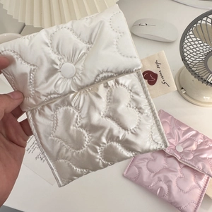 Close-up of quilted heart pattern satin storage pouch with Sodakka label and button closure