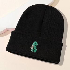 Nahaufnahme der grünen Dino-Stickerei auf einer schwarzen Strickmütze für den Winter