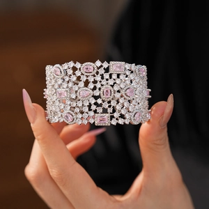Close-up of wide hollow silver-tone bracelet featuring pink and white sparkling zircons